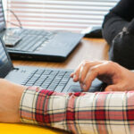 Photo d'illustration. Une personne utilise le clavier d'un ordinateur portable. Un zoom est réalisé sur ses mains.